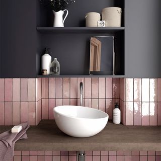 An under stairs bathroom with a grey wall and pink tiles
