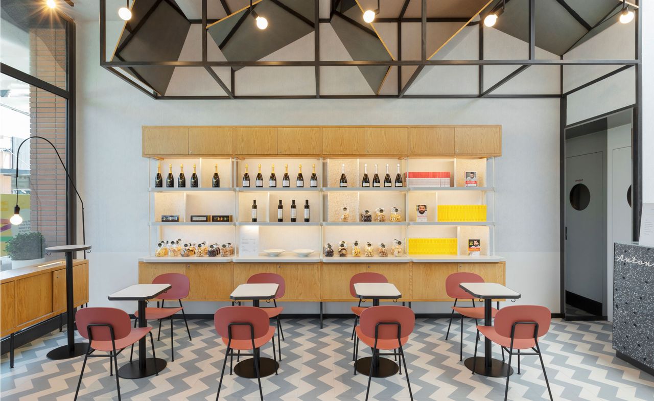 Part of restaurant with tables and chairs and shelves with bottles of wine on it