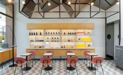 Part of restaurant with tables and chairs and shelves with bottles of wine on it