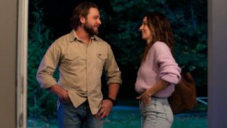 Max Thieriot as Bode looking at Alona Tal as Chloe in Fire Country. They're both smiling.