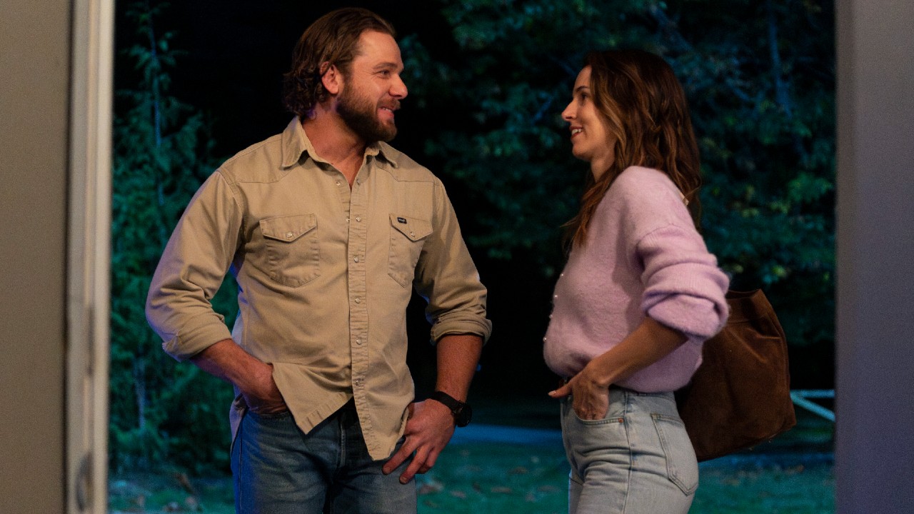 Max Thieriot as Bode looking at Alona Tal as Chloe in Fire Country. They're both smiling.