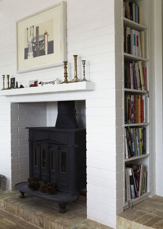 fire in white brick fireplace next to book shelf