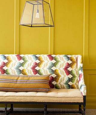 yellow painted paneled walls with contrasting upholstered sofa
