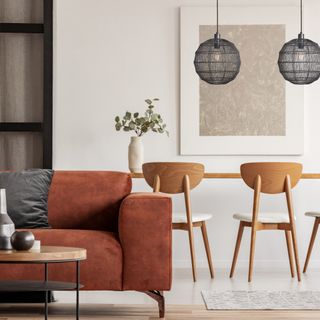 living room colour schemes, white and tan living and dining space, tan sofa, artwork, dark grey pendants, wooden chairs and table, rug