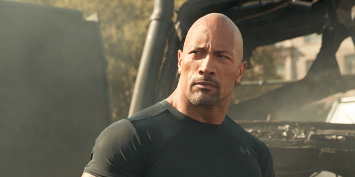 Luke Hobbs (Dwayne &#039;The Rock&#039; Johnson) stands in front of a burnt out vehicle in &#039;Fast &amp; Furious Supercharged&#039;