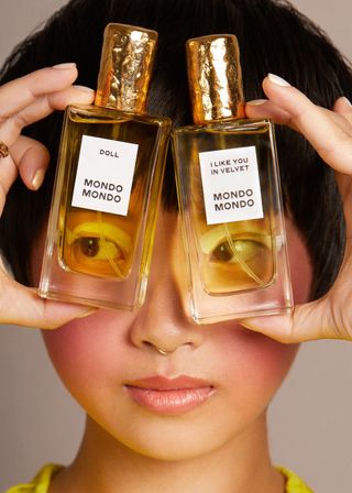 mondo mondo doll fragrance and I Like You Velvet fragrance being held up in front of girls face