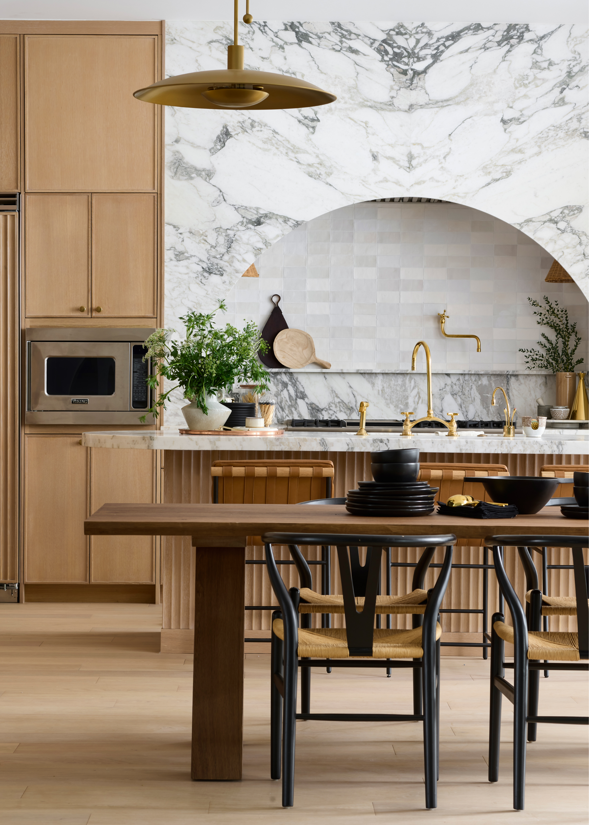 a wood and marble kitchen with an arched hood