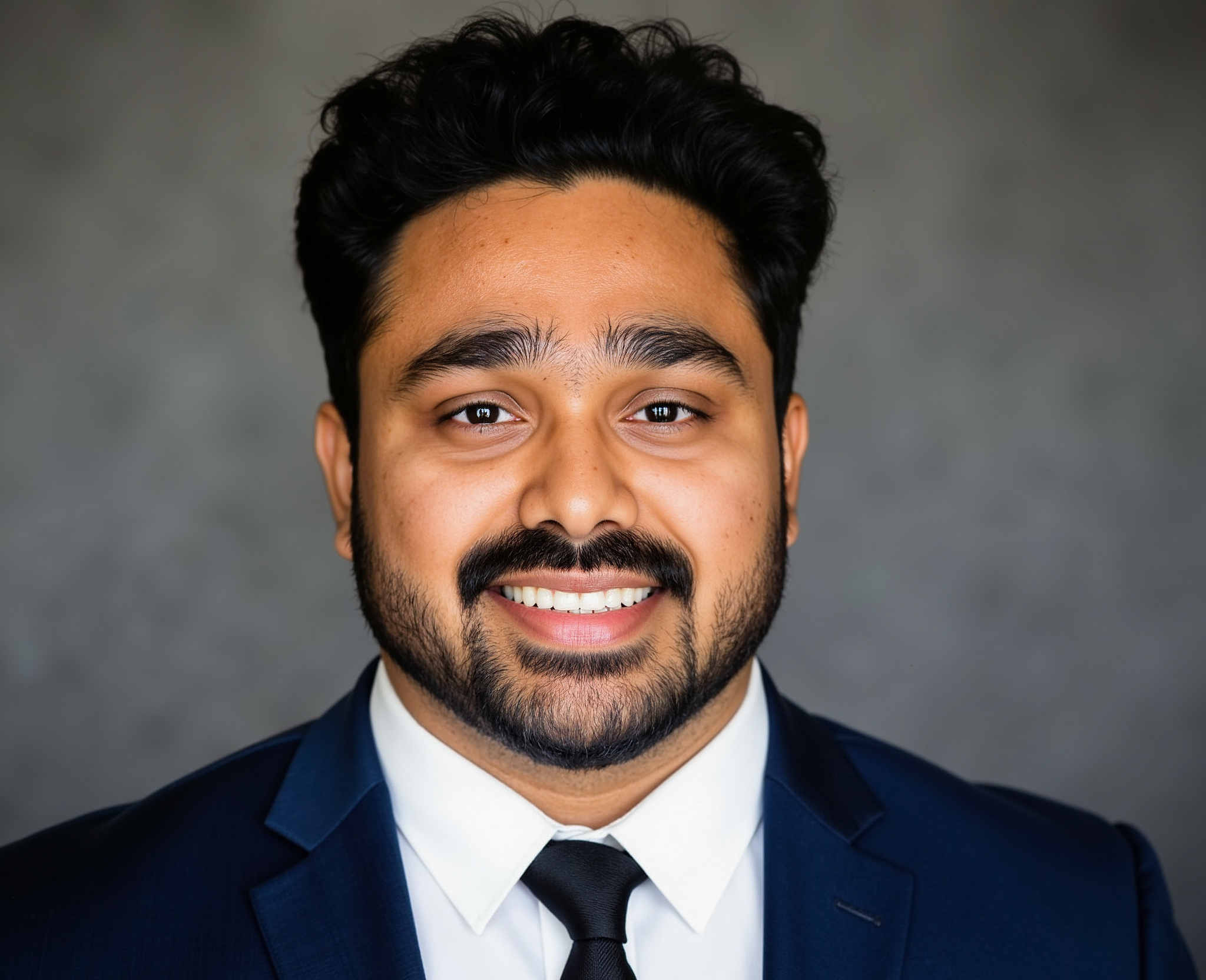 Formal headshot of Hrishikesh Gopal Tawade wearing a suit and tie, against blurred-out gray background.