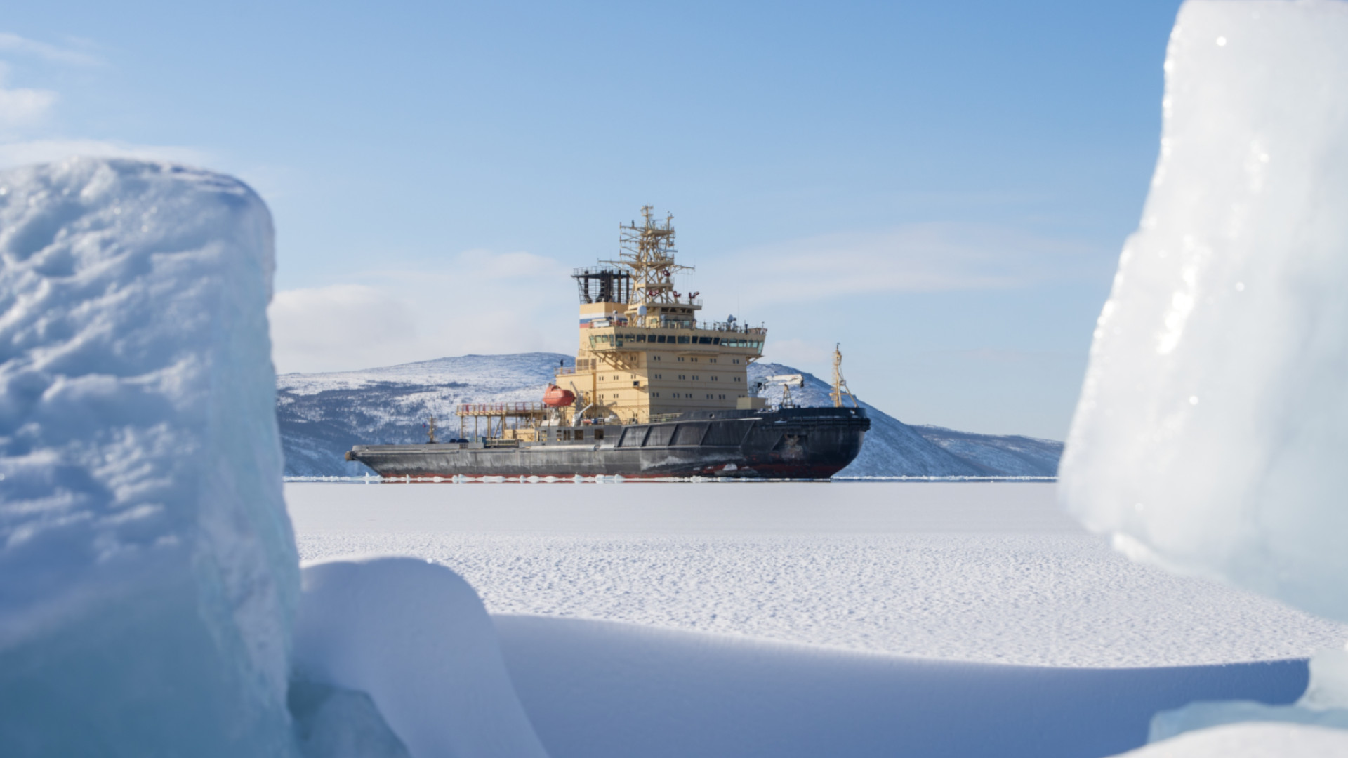 A winter landscape with an icebreaker amidst the ice. A view of the icebreaker in a frozen bay. Ice floes in the foreground.