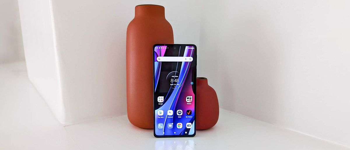 Motorola Edge Plus 2022 resting against two vases on a white surface