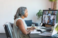 An older woman who is a remote worker is on a video call with colleagues.