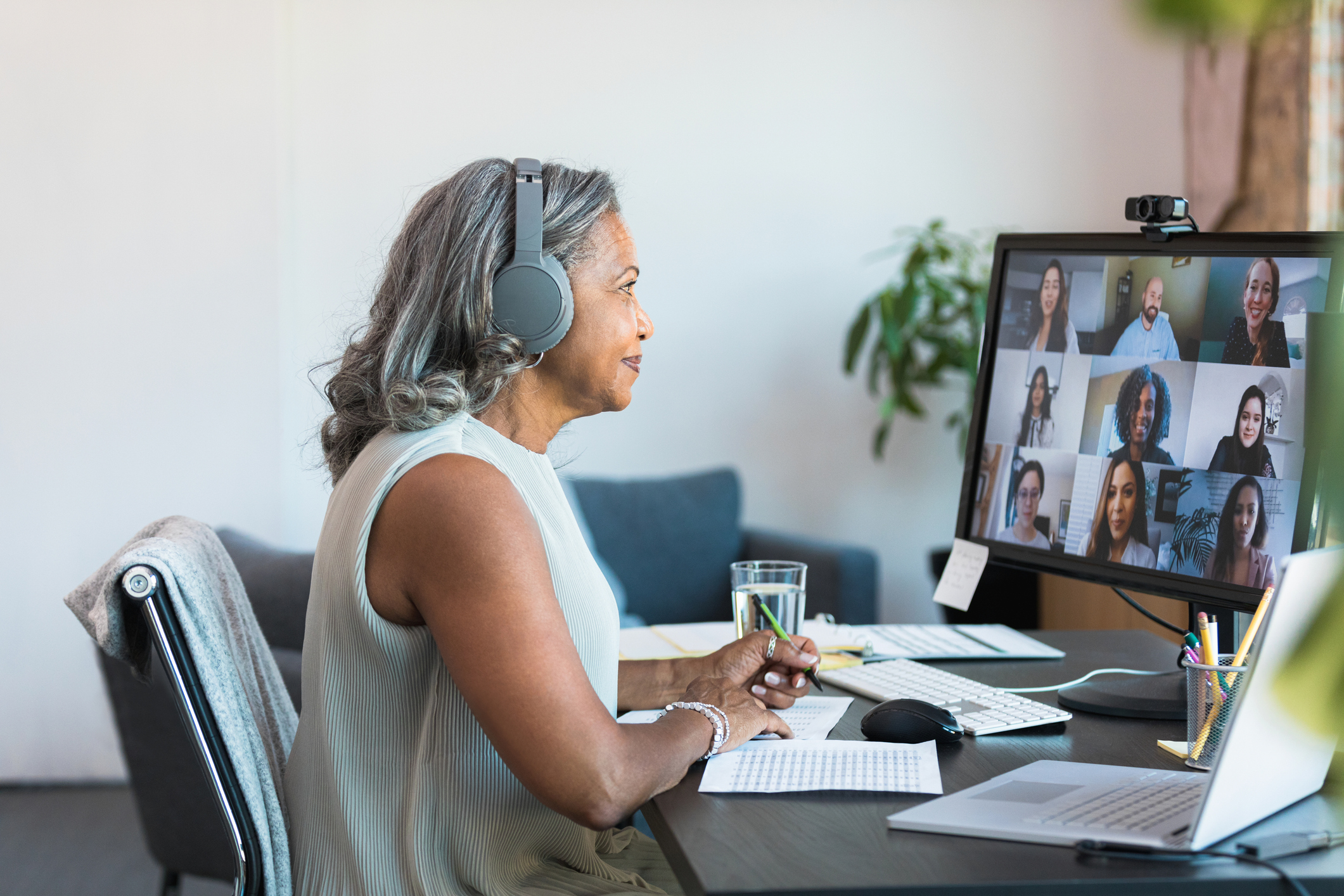 An older woman who is a remote worker is on a video call with colleagues.