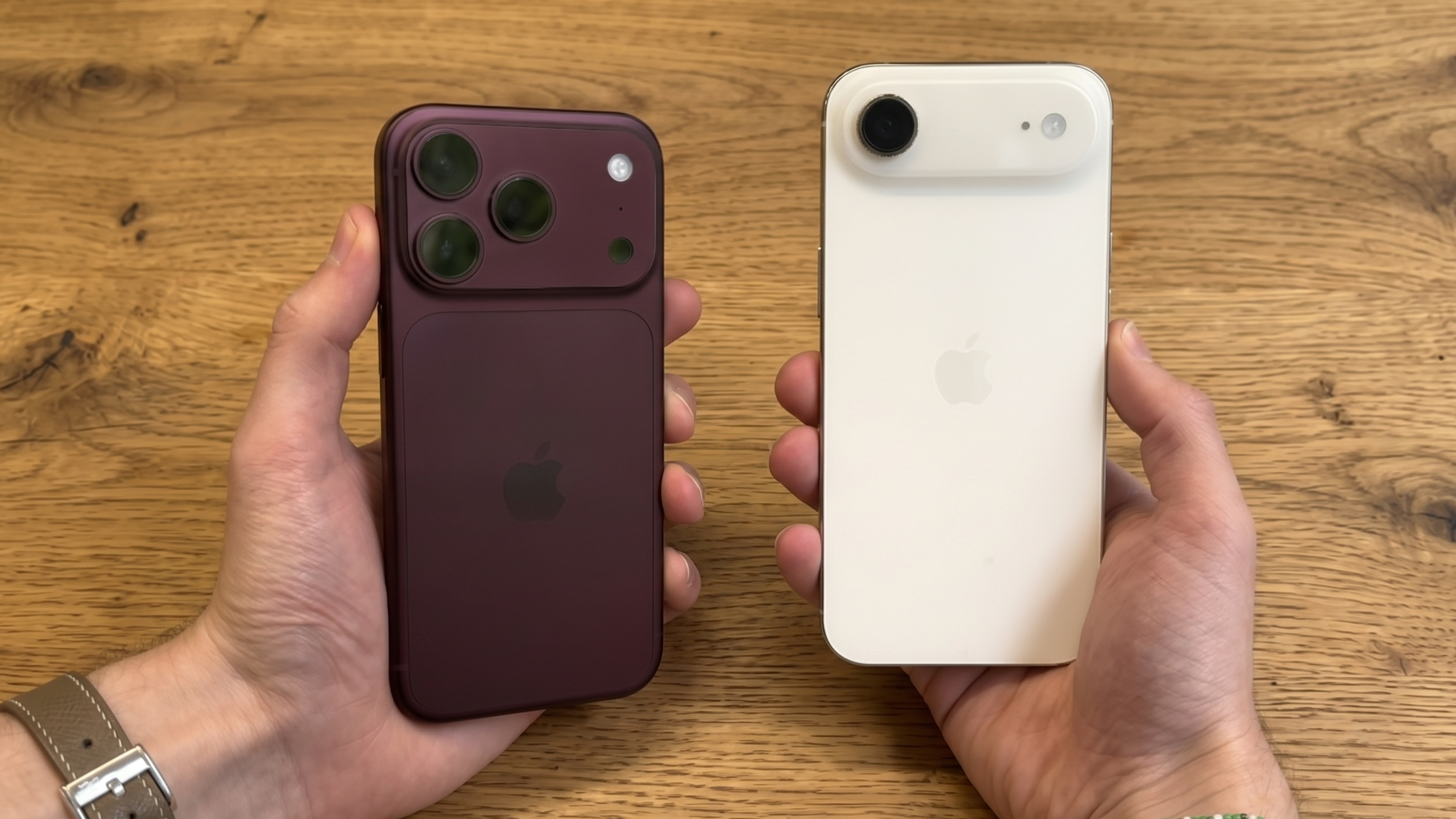 The iPhone 18 Pro and iPhone Air being held in opposite hands atop a wooden table