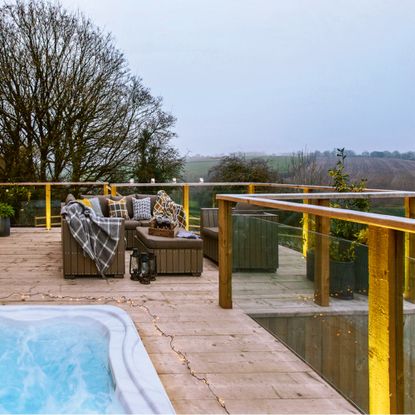 Wooden deck with a view over the landscape, with a hot tub and seating