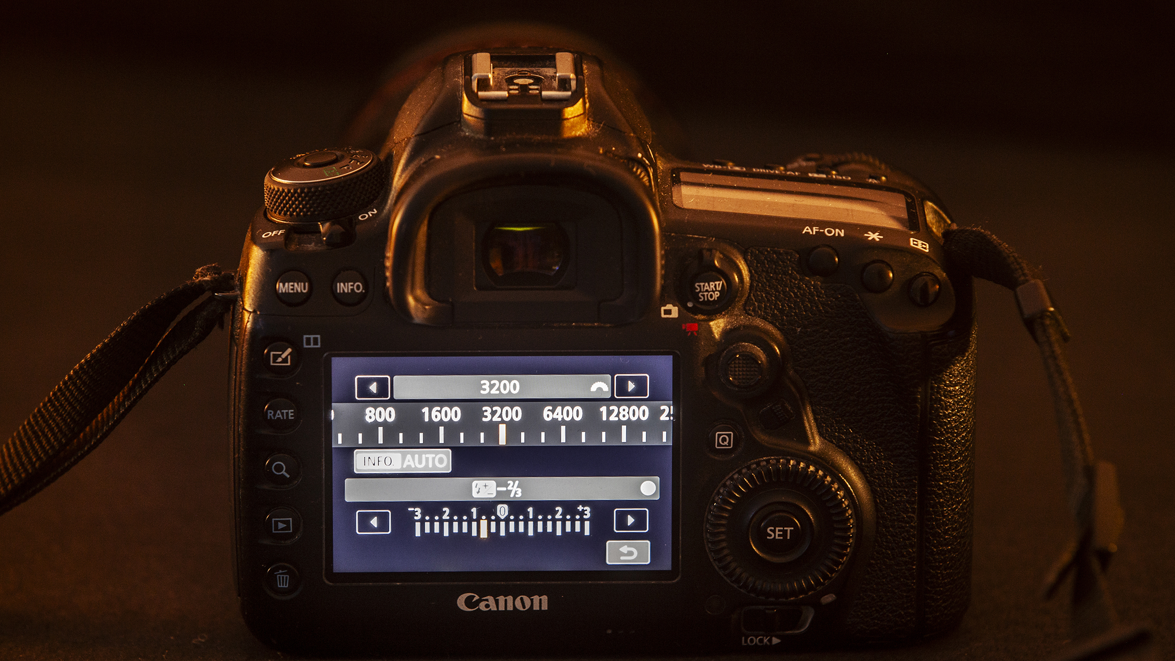 A DSLR camera viewed from the back showing its LCD screen with settings, including ISO 3200, in dim lighting, conveying a focused and technical atmosphere