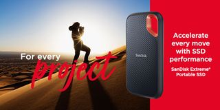 A SanDisk Extreme Portable External SSD next to a person on a sand dune