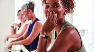 Three women standing at ballet barre wearing Fitbit Luxe watches