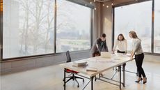 Three businesspeople gather around a temporary table in a new workspace.