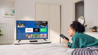 Woman lying in front of TV displaying Sky's entertainment center with various media apps