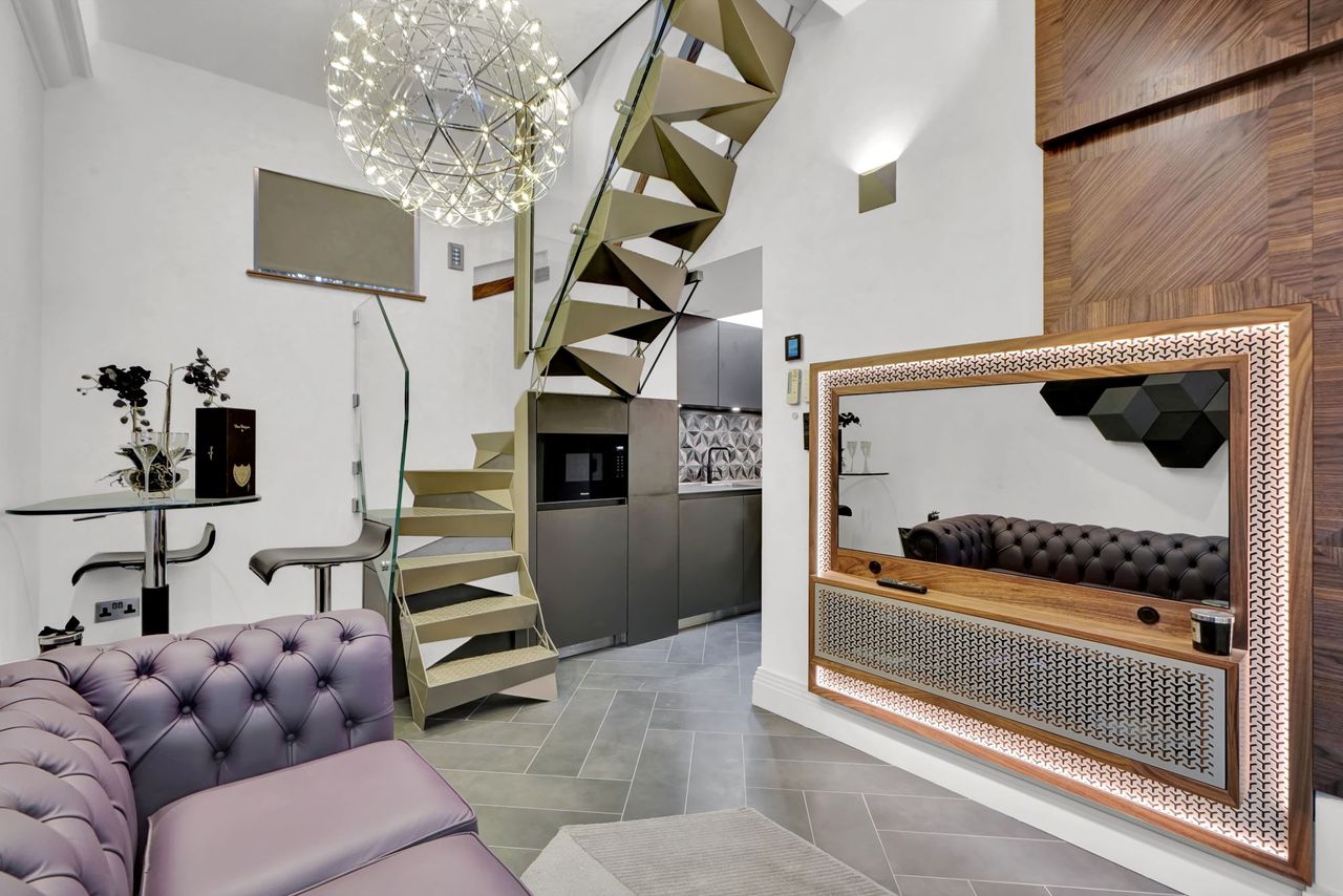 The living room in the small home with grey floor and an electric heater on the wall