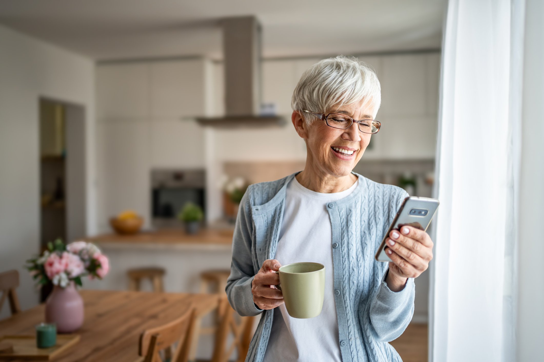 An elderly woman, a pensioner, uses a smartphone at home 