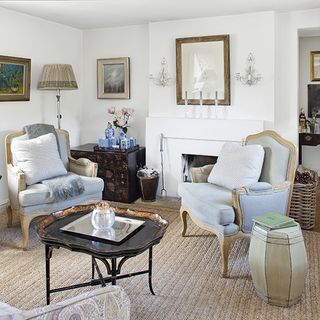 living room with white wall and carpet flooring with arm chairs and cushions