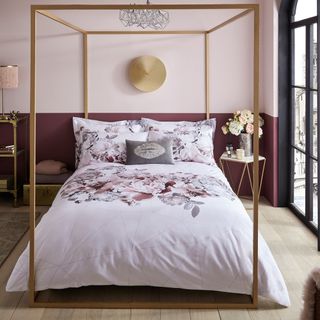 bedroom with wooden flooring and maroon colour and light pink wall with golden clock on wall
