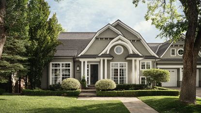 Gray shingle-style Salt Lake City home with white trim, curved gables and a tree-framed front lawn.