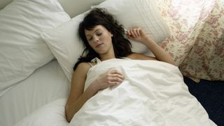 Woman sleeping on her back under a plush, white blanket