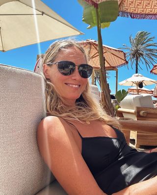 Lisa Oxenham relaxing under an umbrella in a black swimsuit.