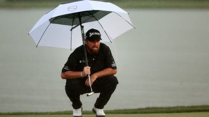 Shane Lowry hides under his umbrella as the heavens opened just as he was about to tee off the final hole of the Honda Classic