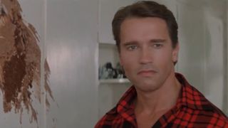 Arnold Schwarzenegger stands in a kitchen ruined by a cake in Raw Deal