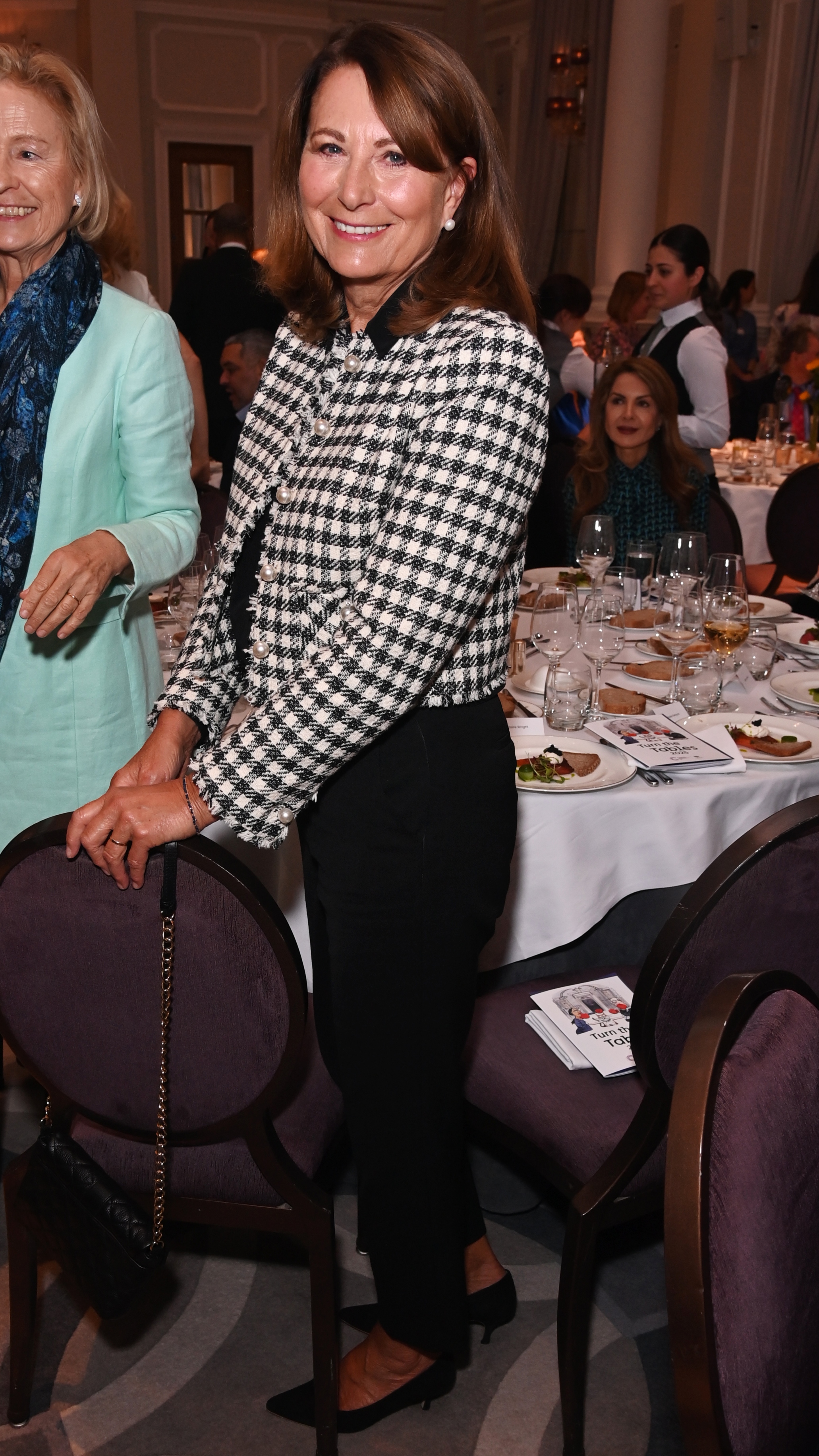 Carole Middleton stands, with her hands resting on the back of a chair, at the Turn The Tables 2025 event