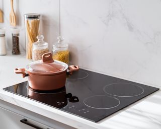 Black stove top with deep red ceramic pan on top