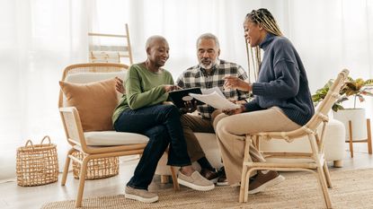 An older couple go over paperwork with a woman in their living room.