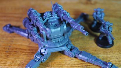 Warhammer The Horus Heresy Saturnine gun turret and models on a wooden surface