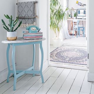 hallway with blue side table and white floorboards