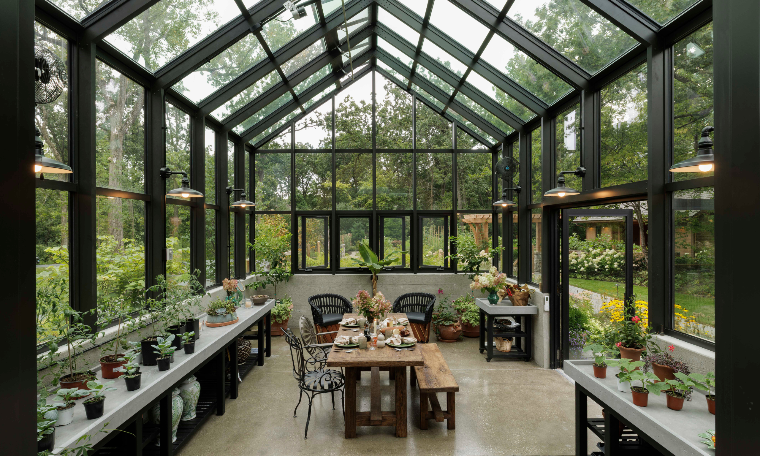 Interior of modern, black framed conservatory with potted plants and dining table