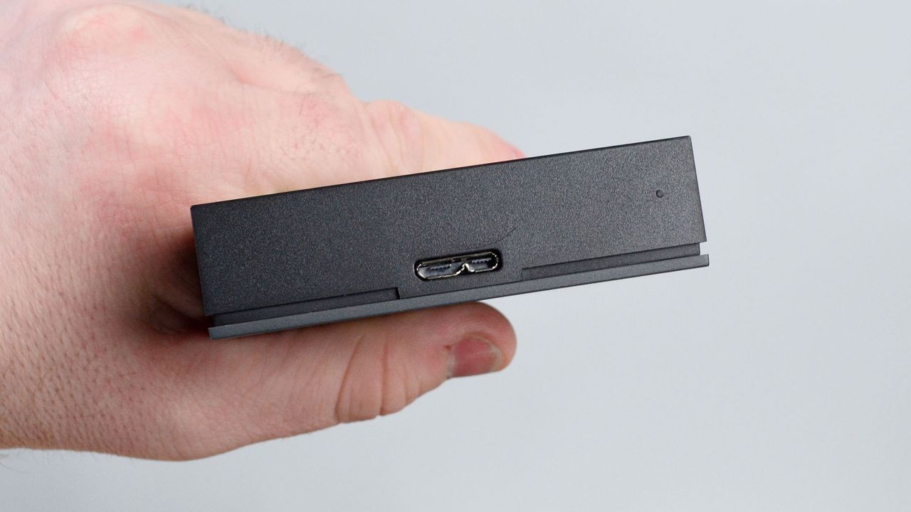 A masculine hand holding a Seagate FireCuda external gaming hard drive