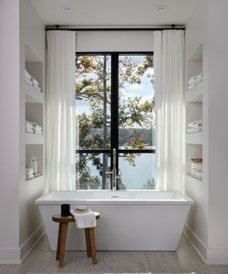 alcove bath tub with view of lake and trees