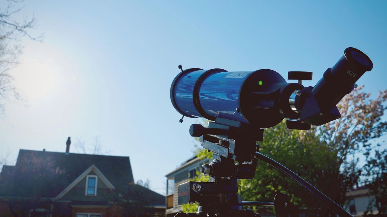 iOptron 80mm white light solar telescope aimed at the sun hanging in the sky over a house