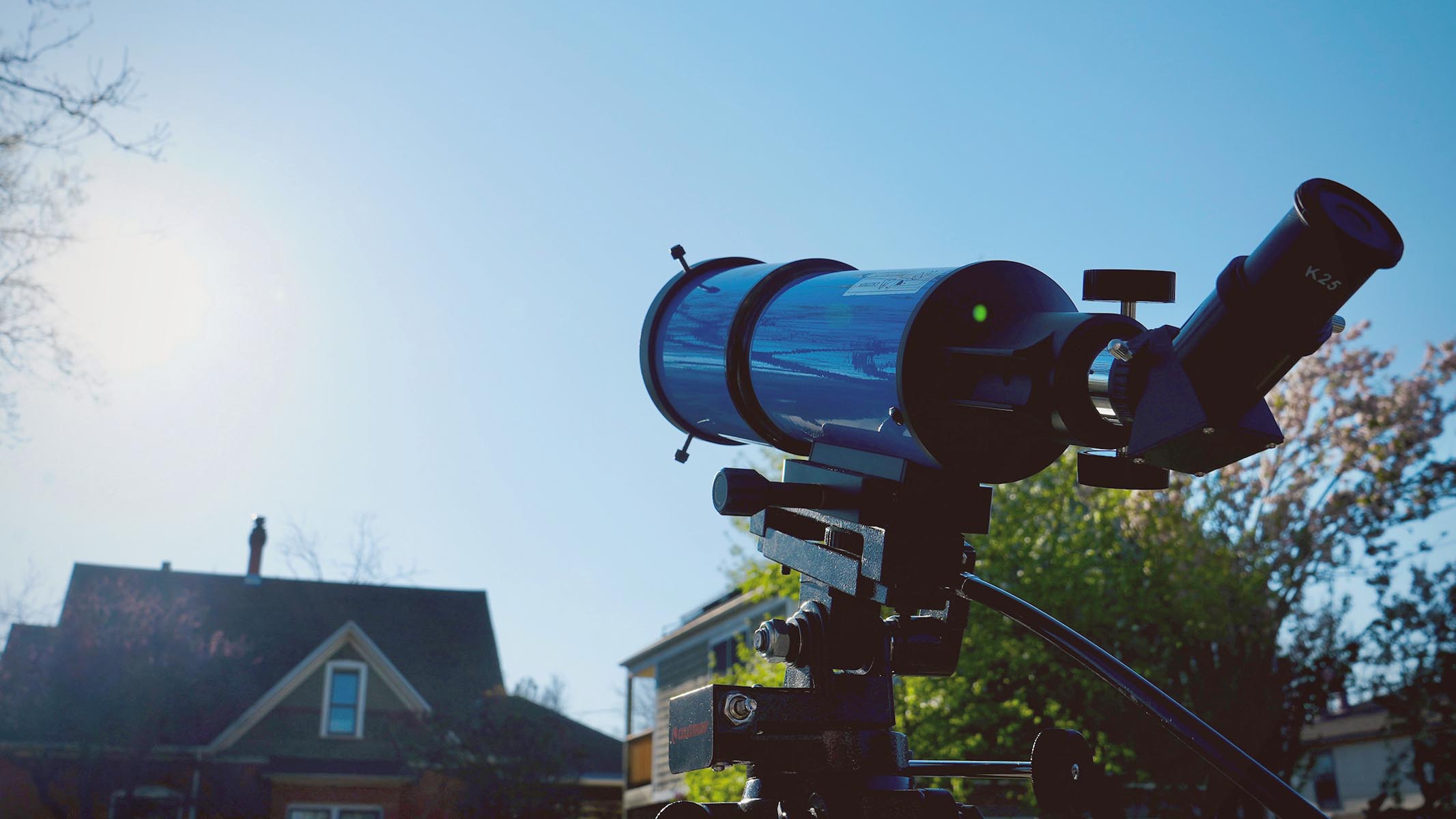 iOptron 80mm white light solar telescope aimed at the sun hanging in the sky over a house