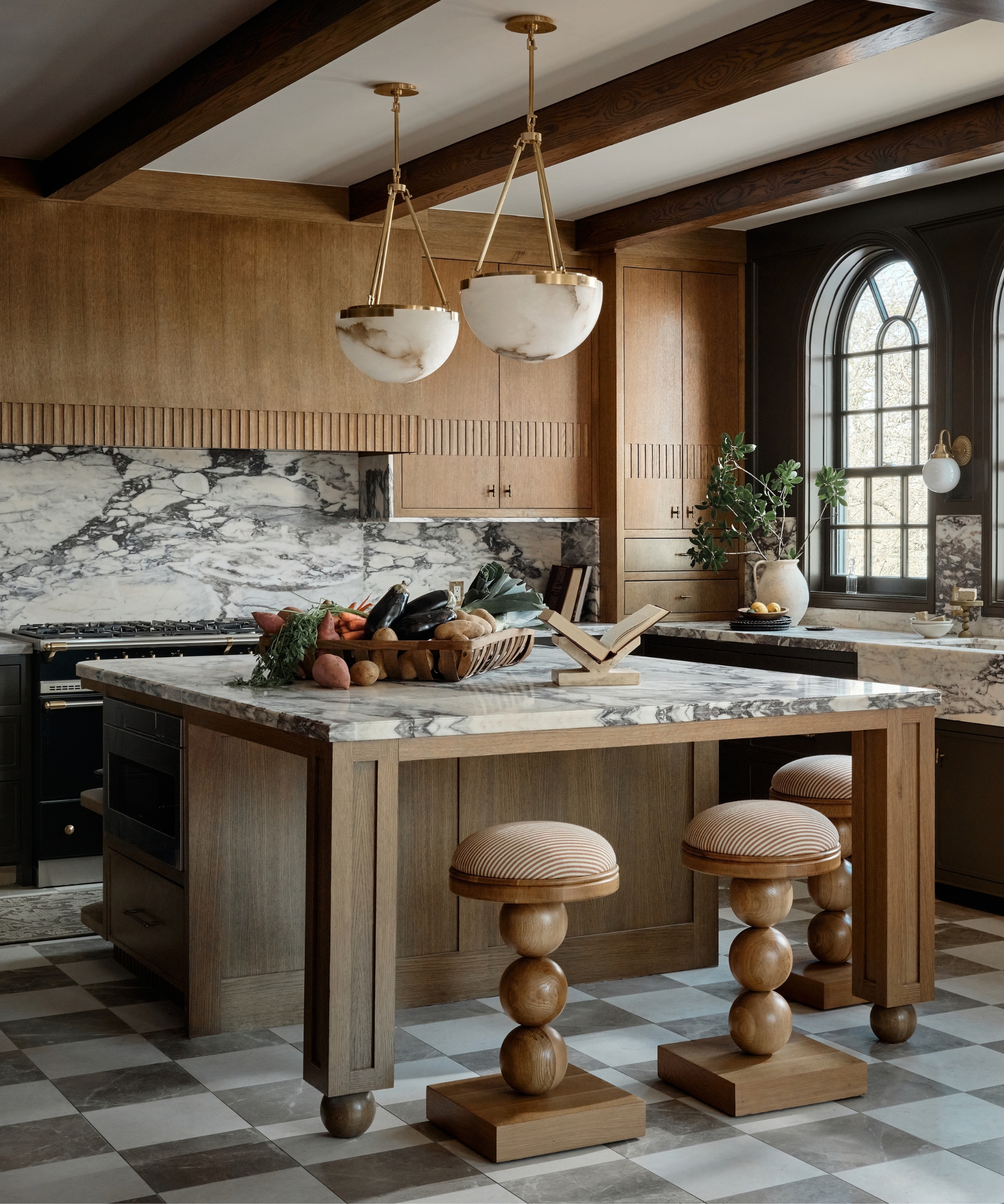 A wooden kitchen with a large island featuring paneled leg details and oversized bobbin stools