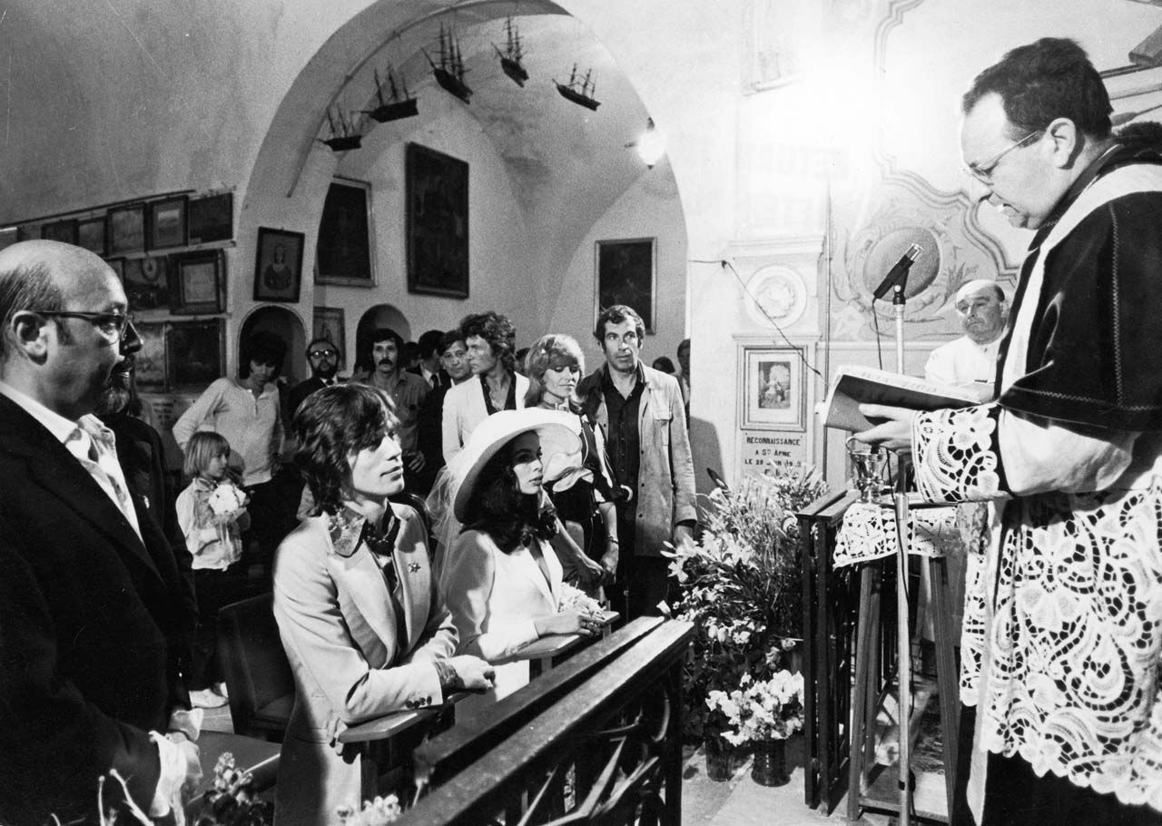 Mick Jagger kneels next to Bianca Jagger during their wedding, as French director Roger Vadim and Nathalie Delon look on. Keef hovers in the background.