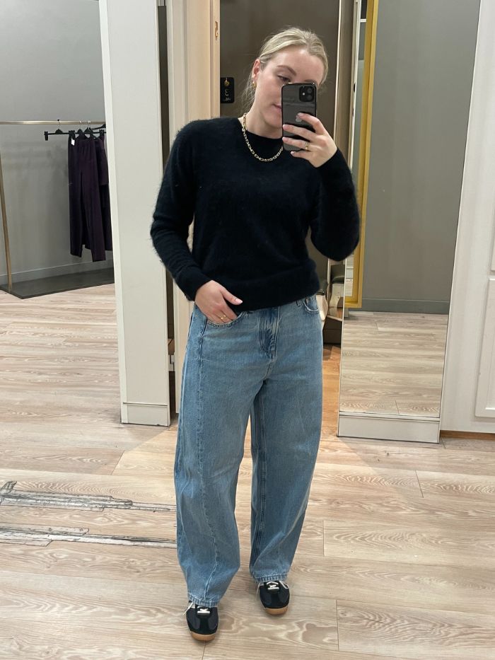 Woman wears black cashmere jumper and blue barrel leg jeans