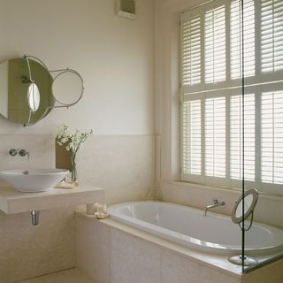 white bedroom with white bathtub and window shutters