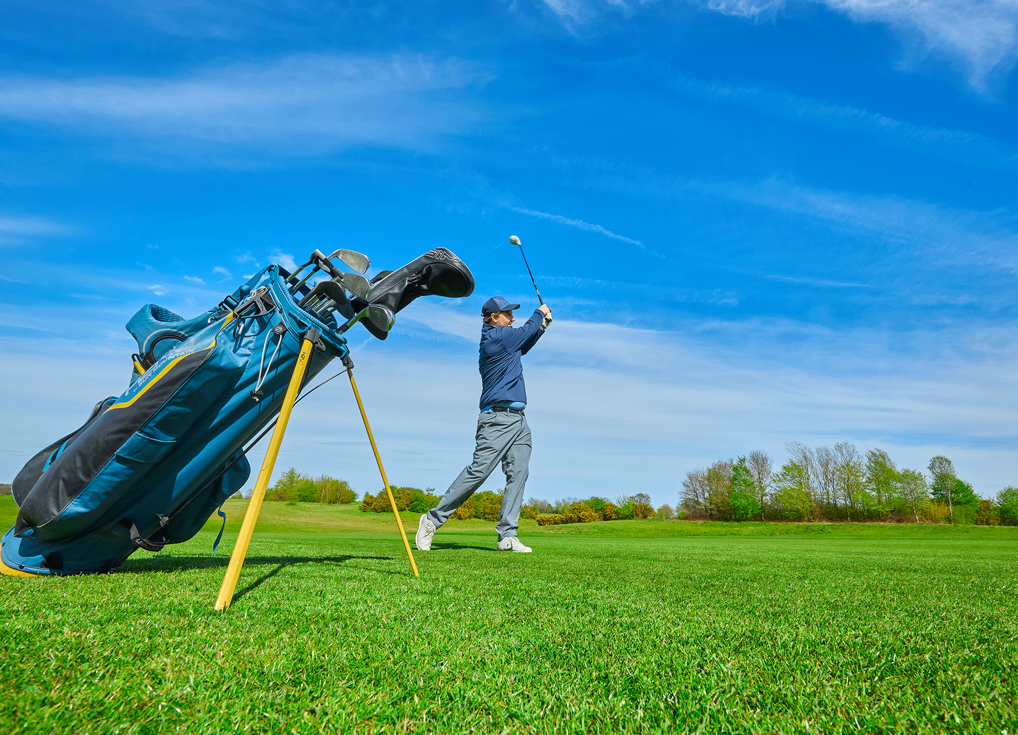 Male amateur golfer in the finish position after hitting a fairway wood into a par-5 green
