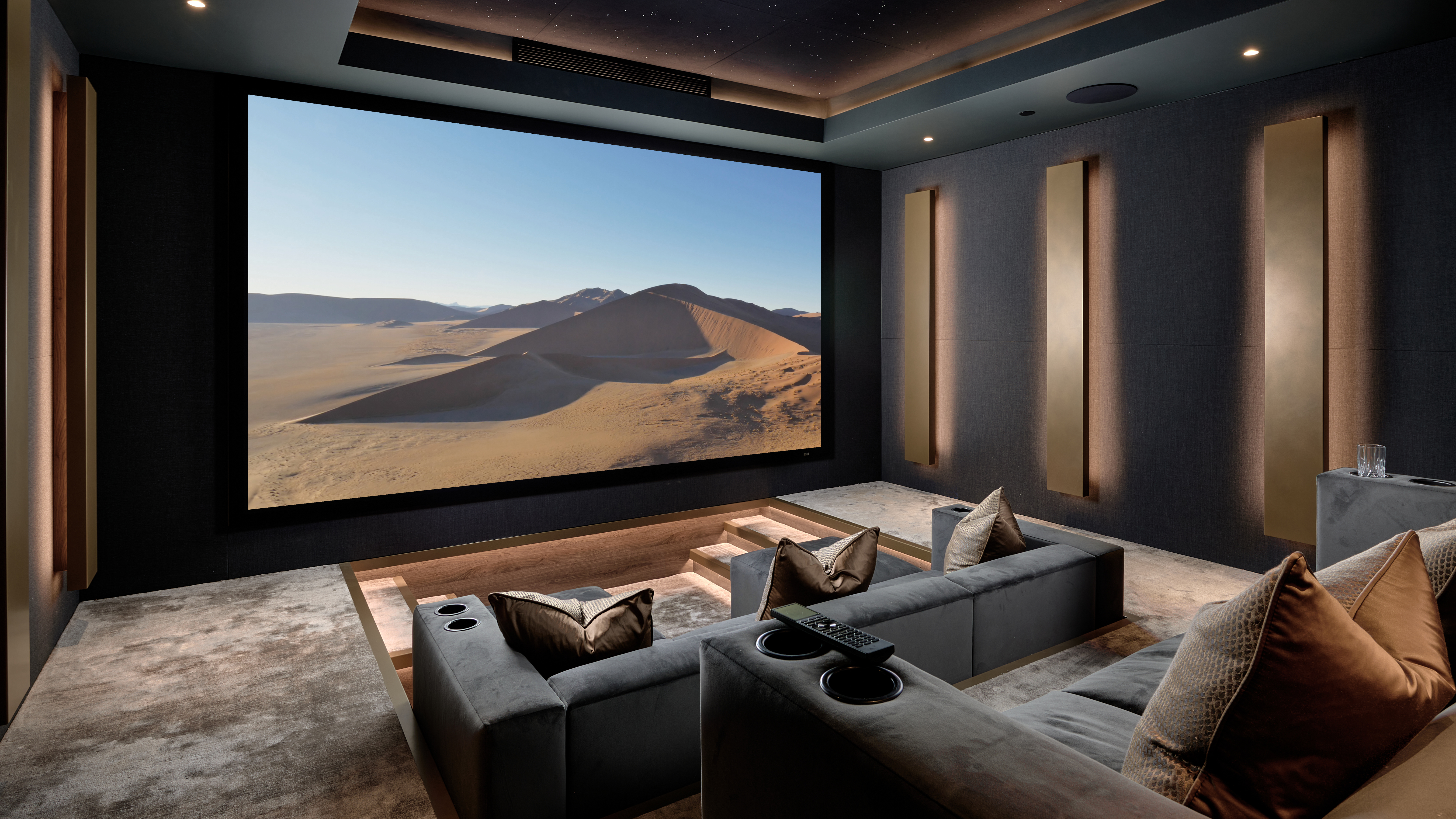 A home theater with plush gray seats and a bright projector screen