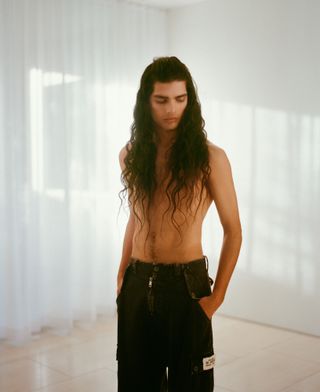 Shirtless man with long hair in jeans in Californian modernist home