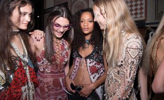 Models wearing transparent floral top and artisan jewelry.